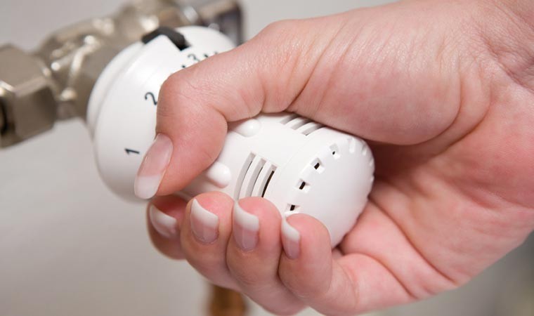 Woman's hand on radiator thermostat