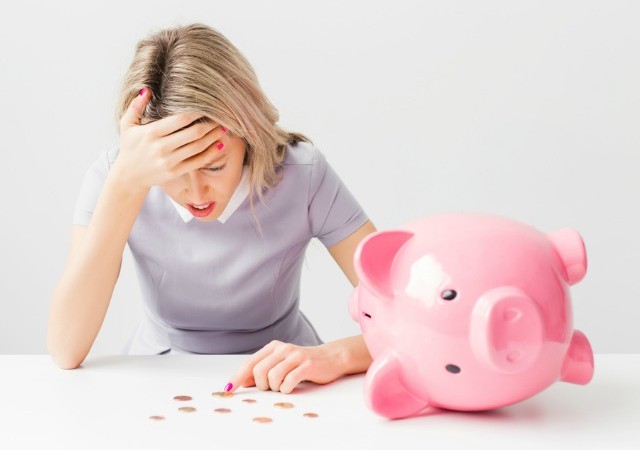 Unhappy woman with piggy bank and coins