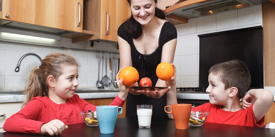 Mum in kitchen offering kids fruit