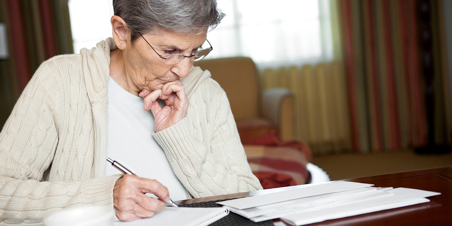 Senior Woman Paying Bills At Home In Her Office