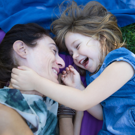 Girl And Mother Laughing Lying In The Park