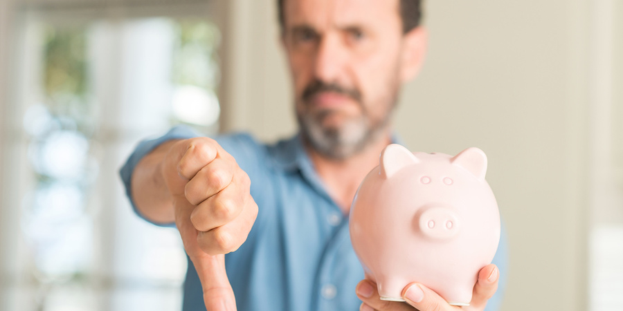 Man with thumbs down holding piggybank