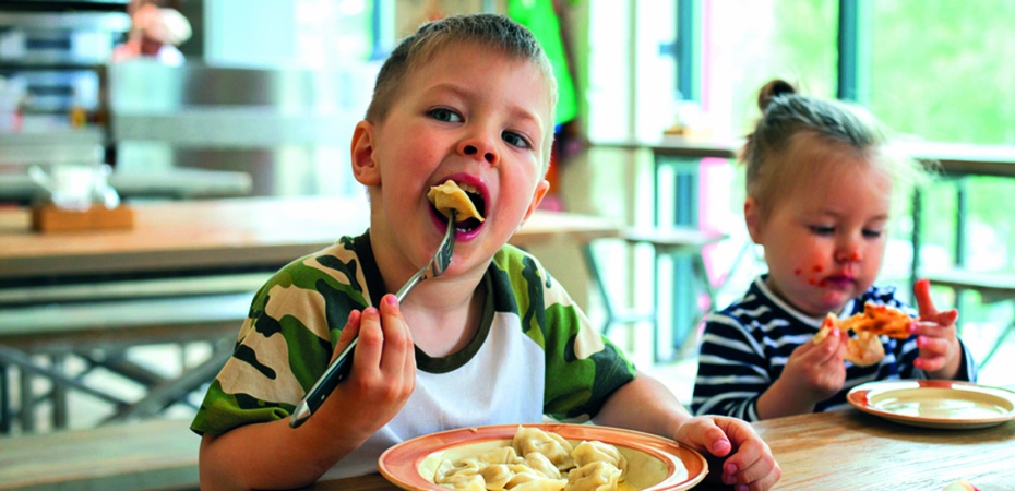 Young children eating pizza and pasta