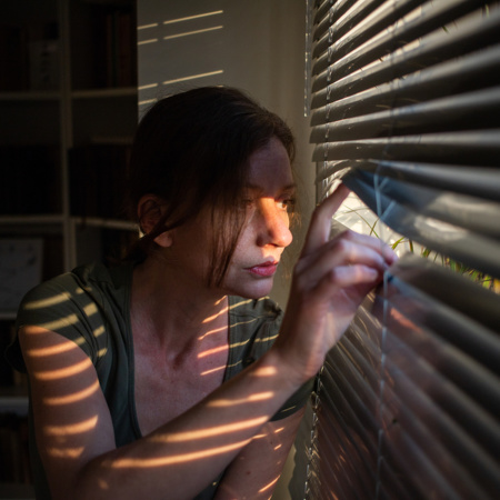 Woman self isolated at home pensive looking out of window