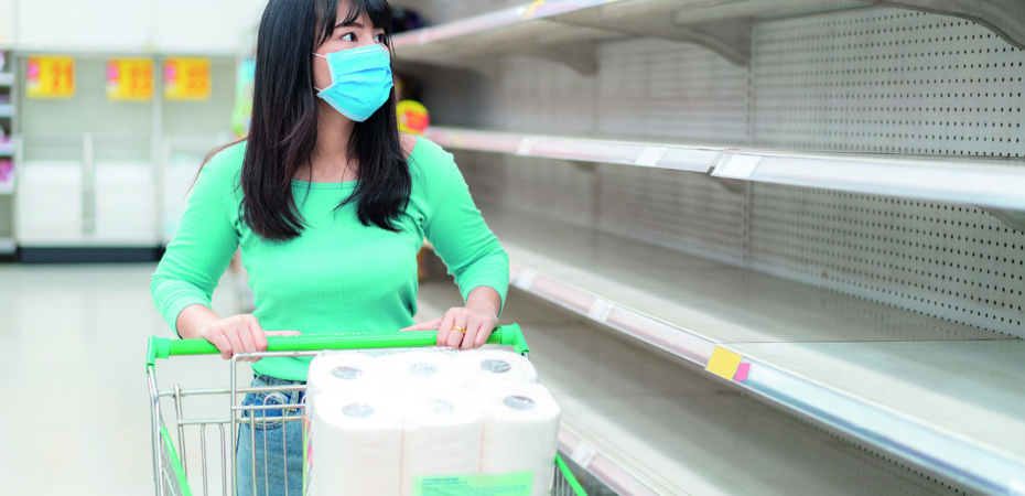 Woman with mask looking at empty supermarket shelves