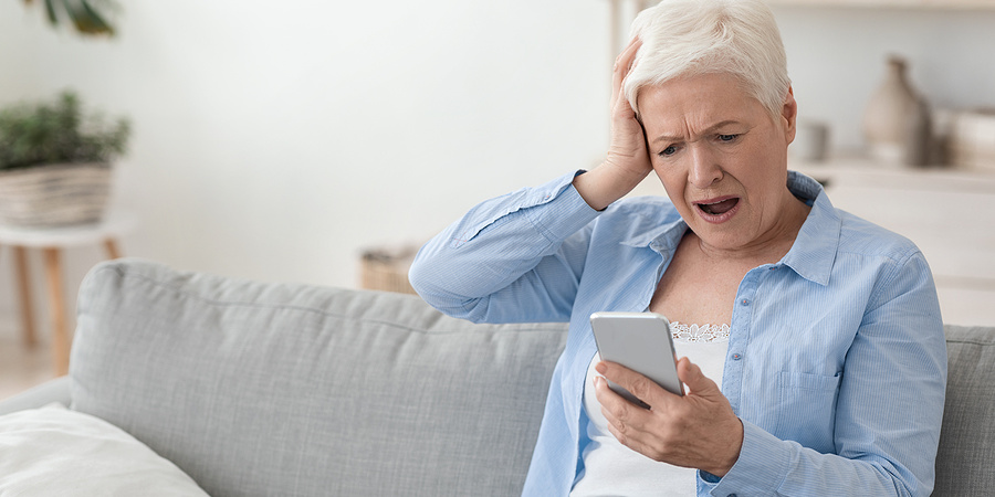 Shocked older woman looking at mobile phone