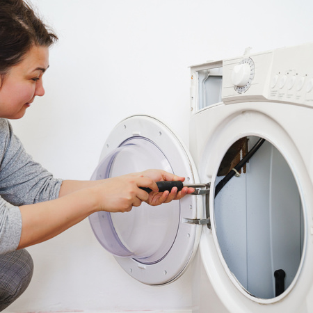 Woman repairing door on washing machine door