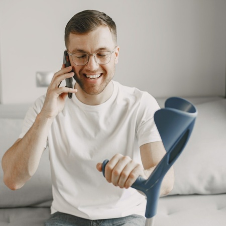 Man with crutches speaking on the phone