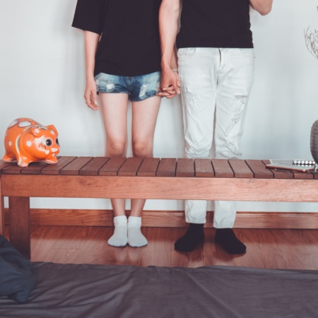 Couple holding hands with piggy bank in foreground