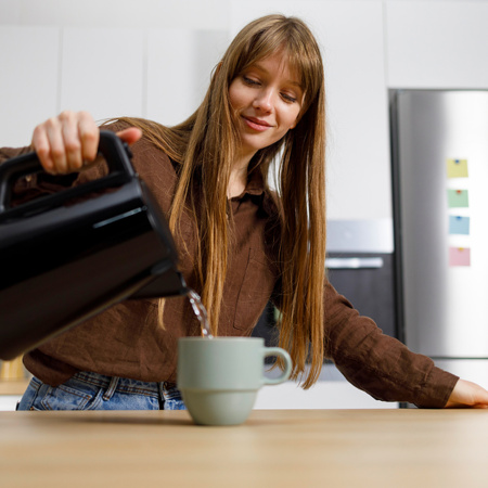 Woman pouring water from a kettle into a cup