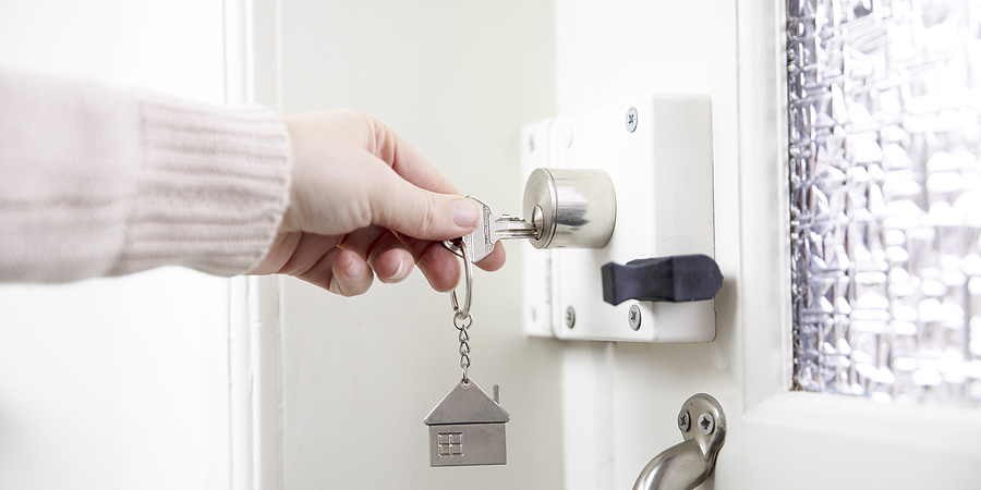 Woman using a key to unlock a front door