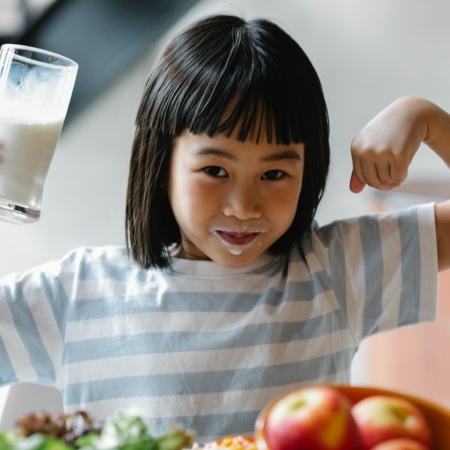 Happy little girl drinking milk