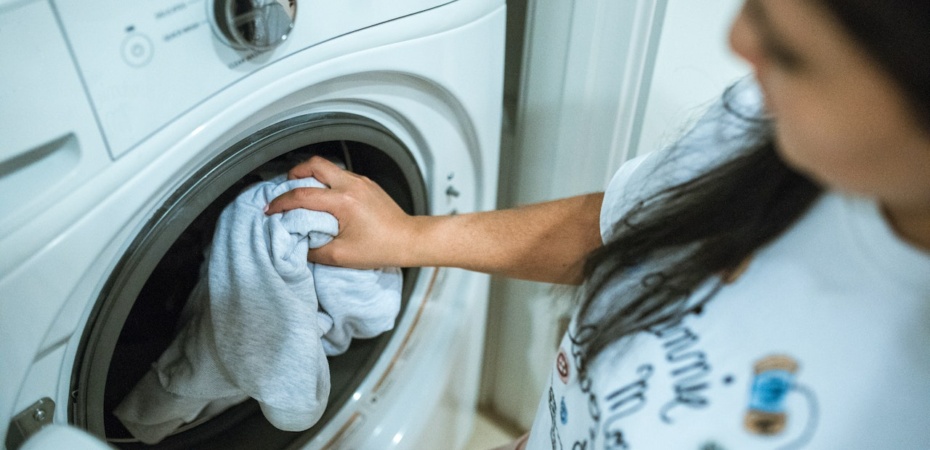 Woman putting clothes into washing machine