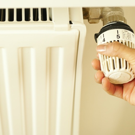 Person turning down a radiator dial