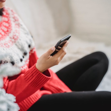 Woman in a Christmas jumper looking at her phone