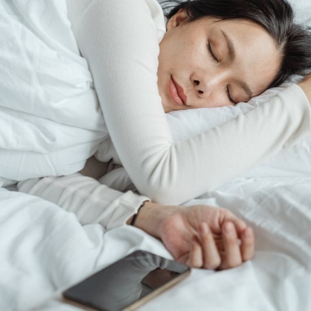 Woman sleeping with mobile phone beside her