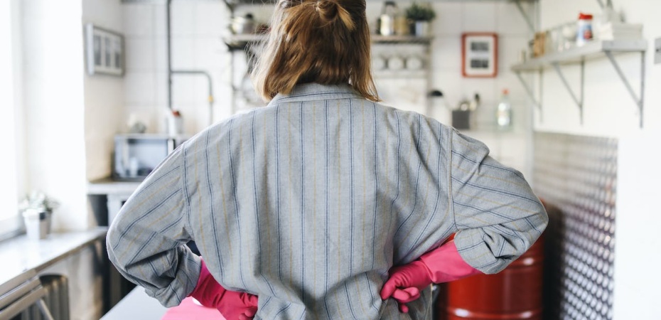 Woman in rubber gloves looking at her kitchen