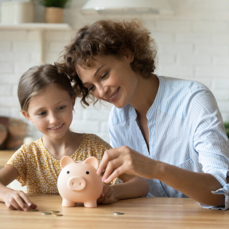 Mother and daughter putting coins in piggy bank
