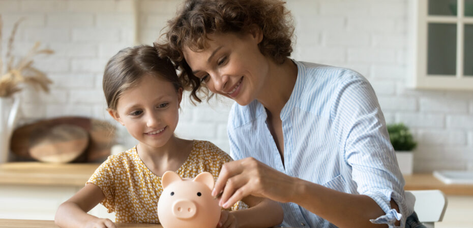 Mother and daughter putting coins in piggy bank